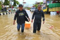 Ketua AJKT Sukriadi didampingi Anggota Firdauz tampak sedang mendistribusikan bantuan makanan di tengah banjir Sangatta, Senin (21/3/2022). (foto: AJKT)